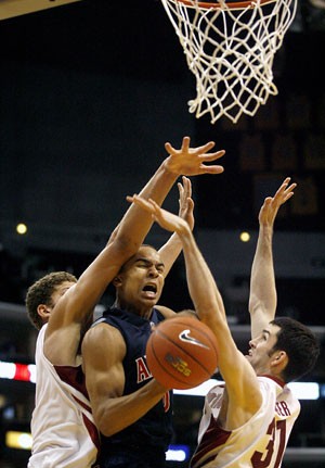 Arizonas Jerryd Bayless is fouled by Stanford forward Brook Lopez (left) and center Taj Finger in the second half of the Wildcats 75-64 defeat last night at the Pacific Life Pac-10 Tournament in Los Angeles.