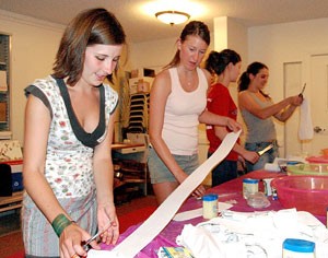 Sophomore Erin Staadecker, left, and freshman Amy Kunkz measure paper strips to be used for breast molds at the Womens Studies Love Your Body event last night. The event began with a panel discussion on different womens issues and concluded with the group making papier-machǸ breast molds and decorating them.