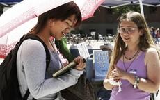 Cindy K. Bana, a visual communications freshman, picks up a plantable Earth Day business card from Jennifer Tobin, a chemical engineering senior, Tuesday on the UA Mall in preparation for Earth Day today.