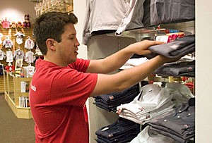 Family studies and human development senior Carlos Chavez stacks shirts yesterday at the new A-Store in the Park Place Mall.  