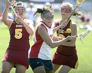 UA freshman Kayla Alloway fights off two USC lacrosse players Sunday at Murphey Stadium. She and the rest of the womens lacrosse team continue to struggle this season, with its only two wins coming from forfeits.