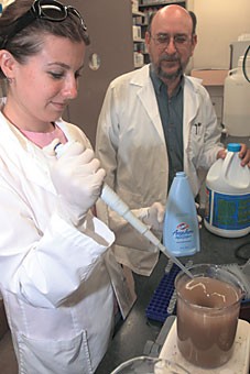 Microbiology professor Chuck Gerba and microbiology graduate student Marisa Chattman perform a procedure to purify contaminated water using household items, such as Clorox.
