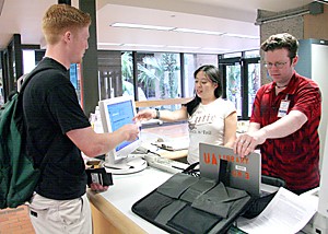 Taylor House / Arizona Daily Wildcat

Undeclared freshman Eric Williams returns a laptop to the Main librarys loan program with the help of UA library staff Nikki Lee and Travis Teetor Monday afternoon. Mac and PC laptops are available for 4 hour loans from the information desk at the Main Library.
