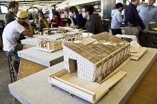 Small-scale models sit before architecture students who have been designing and building solar powered single-family home as participants in the Solar Decathlon.