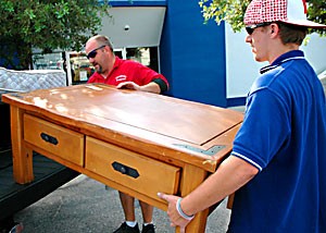 Mike Swanson, left, and Andy Swanson of Swansons Furniture load a coffee table into a UA students truck Friday afternoon. Swansons Furniture offers UA students 10 percent off purchases with a student ID card.