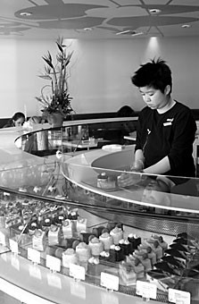 Bakerzin supervisor Yen Hoe arranges pastries in a display case. The new bakery on University Boulevard will celebrate its grand opening at the end of February.