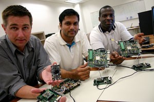 From left, Kevin Carr, Adarsha Sreeramareddy and Jeff Josiah show off a small-scale prototype that they say can fix itself should it encounter technical difficulties. The students say the software will try to imitate a living organism.