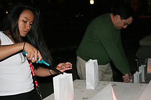 Sharon Claros, hall director of Kaibab-Huachuca Residence Hall, and Brian Shimamoto, director of Asian and Pacific American Student Affairs, light tea candles inside paper bags that have a story written on them about a victim of a hate crime. A candlelight vigil was held last night at the fountain in front of Old Main to remember these victims during the annual Transgender Day of Remembrance.