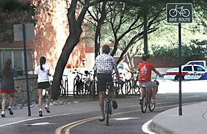 Bike riders and pedestrians travel yesterday afternoon between the Science-Engineering Library and the Henry Koffler building as a police vehicle sits at a stop sign in the distance. UAPD is now making efforts to enforce biking and pedestrian laws in light of the number of traffic accidents on campus.
