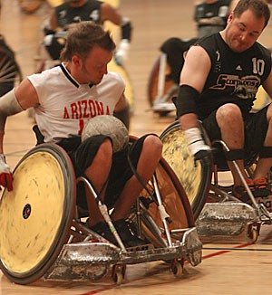 An Arizona Wheelchair Rugby player takes the ball up court during the teams Rugby Rage tournament over the weekend at the Student Recreation Center.
