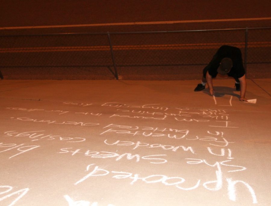 Francis the Poet uses chalk to write a poem by the Speedway Boulevard underpass at 1 a.m. Friday. Francis the Poet writes poems by other authors as well as some originals to provoke thoughts in passersby. 