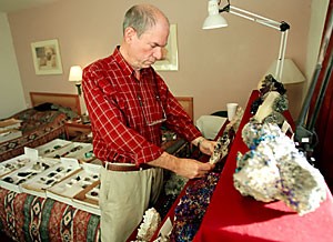 Doug Coulter from Norman, Okla., examines a piece of sphalerite with chalcopyrite and dolomite in his hotel room at the Best Western Executive Inn, 333 W. Drachman St. Coulter is in town for the Tucson Gem, Mineral and Fossil Show.