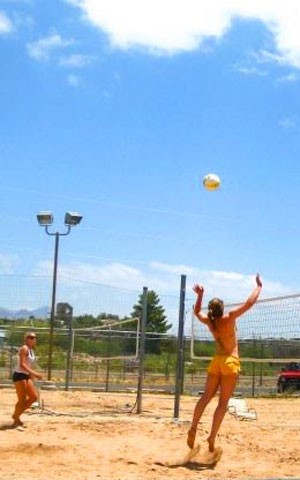 Former Wildcat Audrey Bockerstette, left,  positions herself as UA opposite hitter Randy Goodenough jumps to swat the ball at the Tucson Racquet Club. Wildcat head coach David Rubio said hes all for the addition of sand volleyball unless it takes from his teams indoor competition.