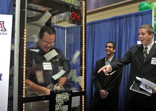 Valentina Martinelli/ Arizona Daily Wildcat

RD Castillo, 29, a business development manager, attempts to grab as much fake money as he can in 20 seconds at the Wall Street Wise booth, while two of the creators of the booth watch, Orr Ben-Zvy, left, a finance senior, and Michael Harrison, an entrepreneurship and management senior.