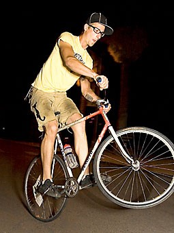 Tim Cheney does a wheelie on his fixed gear bicycle Sunday evening outside of Old Main.  Fixed-gear bikes feature fewer metal parts than road or mountain bikes but can be more perilous to ride. 