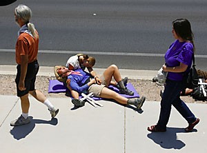Julie Todd, of Denver, Colo., (front) and Mayada Valley of Tucson, re-create a scene of a migrant dying in the desert near the Border Patrols headquarters on Ajo Way in Tucson during the final stretches of the Migrant Trail walk Sunday.