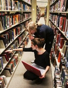 Leah Hartman and Erin Asselta, both theatre arts freshmen, sift through the stacks for books on contemporary theatre scenes Tuesday evening in the Main Library.
