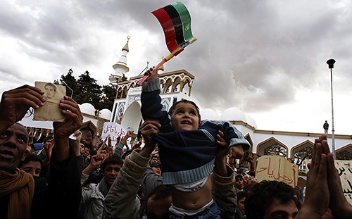 A flag-waving child is hoisted into the air, Wednesday, February 23, 2011, as residents of Darnah, Libya, celebrate the liberation of their town from the control of forces loyal to dictator Moammar Gadhafi. (Luis Sinco/Los Angeles Times/MCT)
