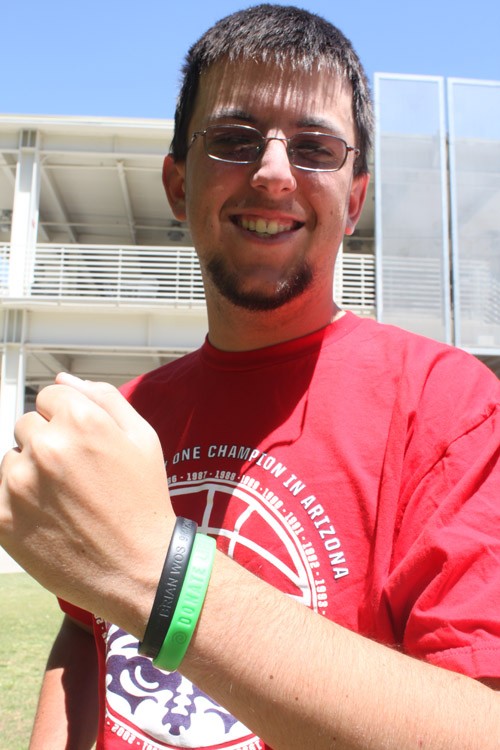 Lisa Beth Earle/ Arizona Daily Wildcat

Kevin Wos, a political science junior, shows the green bracelet he wears proudly advocating organ donation and the black bracelet that is in memory of his late brother Brian. He also sports his Zona Zoo shirt in support of UA athletics of which he says going to games has been a really big part of who he is.