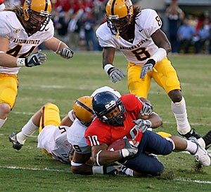 Arizona wide receiver Mike Thomas is tackled by ASU safety Josh Barrett as a host of Sun Devils watch in the second quarter of the Wildcats' 28-14 loss to ASU Nov. 25 at Arizona Stadium. Despite this loss that cost Arizona a bowl berth, the Wildcats took a step in the right direction by improving from 3-8 the past two seasons to 6-6 this year.