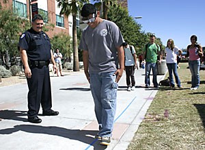 University of Arizona Police Department officer Frank Romero administers the walk-and-turn test to Brian Gonzalez, a physiology freshman, while he wears goggles that simulate the legal blood-alcohol level of .08 percent for the ASUA-run Student Health Advisory Committees drug and alcohol awareness event on the UA Mall yesterday afternoon.