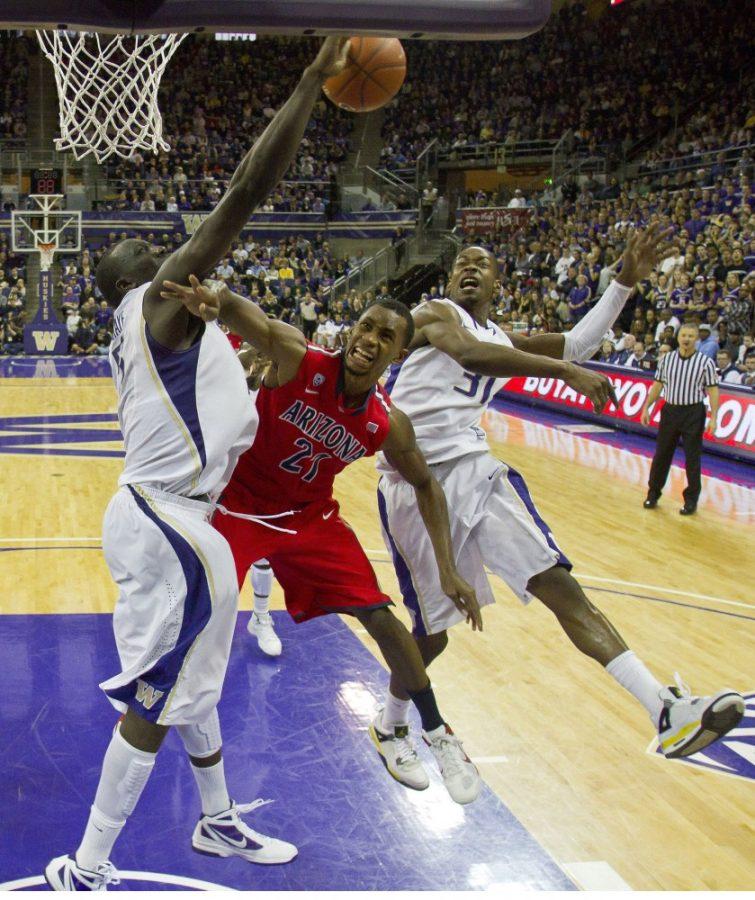 Washington's Aziz N'Diaye, left, swats away a shot by Arizona's Kyle Fogg in the second half at the Alaska Airlines Arena on Saturday, February 18, 2012, in Seattle, Washington. The host Huskies posted a 79-70 triumph. (Dean Rutz/Seattle Times/MCT)  