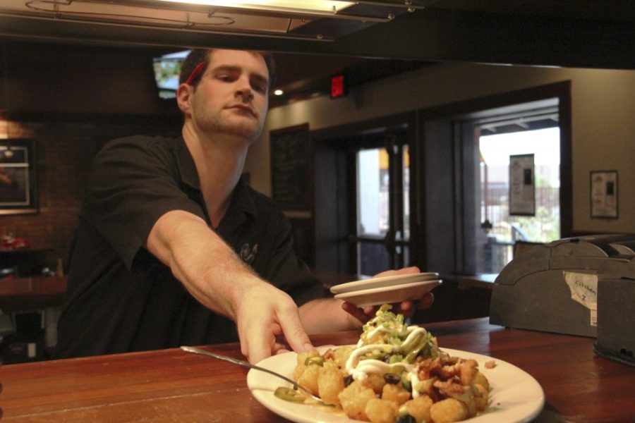 Noelle R. Haro-Gomez/Arizona Summer Wildcat

Will Gushee, a server at Mays Counter, takes Tot-chos to one of his tables. 