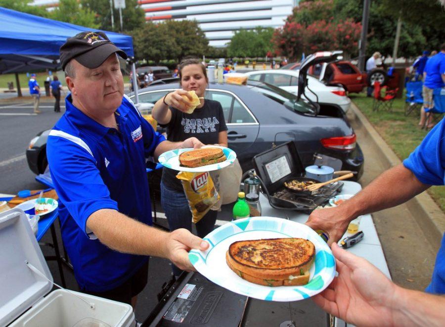 Georgia State University employee Danny Weipert, center, offers a grilled sandwich to a friend as he and Caroline Dotts, right center, tailgate together for Georgia State University's opening football game against South Carolina State in Atlanta, Georgia, August 30, 2012. (Jason Getz/Atlanta Journal-Constitution/MCT)