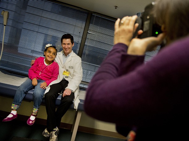 Kalkidan Sirbaro, left, poses with neurosurgeon Samuel Ciricillo at a postoperative checkup, January 23, 2013, in Sacramento, California. The 7-year-old was discovered with a life-threatening brain tumor in Ethiopia; family physician Sarah Jones, taking photo at right, arranged for her care in U.S. (Renee C. Byer/Sacramento Bee/MCT)