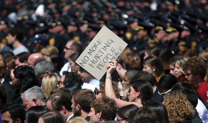 A woman holds a sign bearing the words of 8-year-old bombing victim Martin Richard during the memorial service for MIT police officer Sean A. Collier at Briggs Field in Boston, Massachusetts, Wednesday, April 24, 2013. (John Wilcox/Boston Herald/MCT)