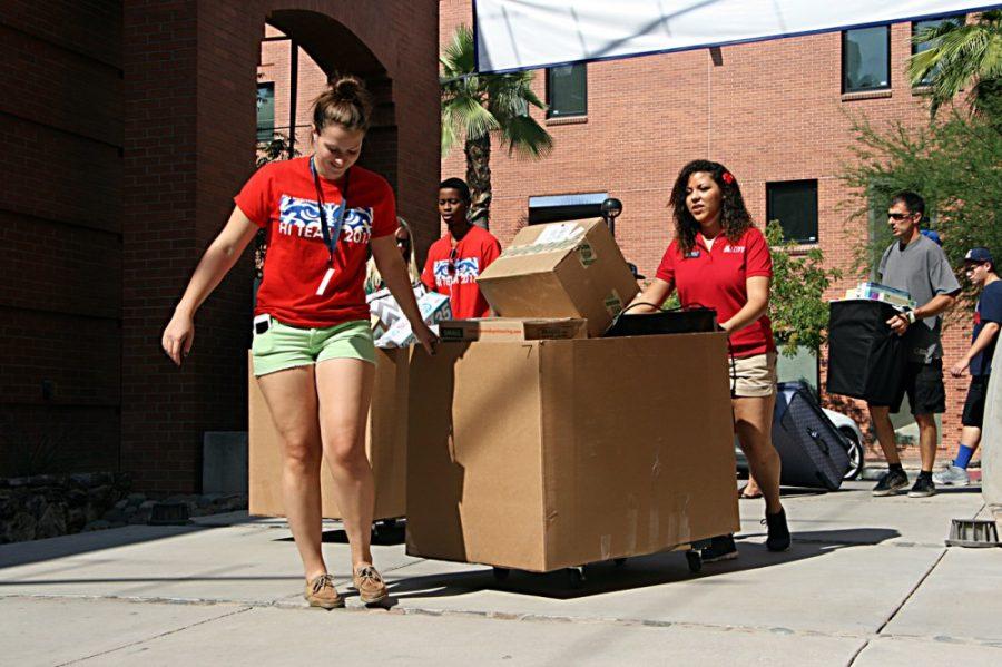 Kaylie Foster (right), a resident assistant at Colonia de la Paz and marketing senior, and Emma Bishop (left), a student volunteer, help move students into the Colonia de la Paz Residence Hall on Thursday, Aug. 22, 2013.  This is the first year that Residence Life used a central check-in system.  