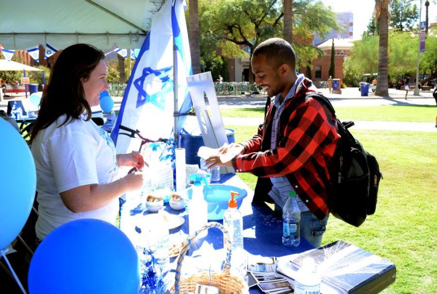 Grace Pierson/ The Daily Wildcat

Volunteer Marisa Offman, a psychology freshman, aids Noeo Teku, an electrical and computer engineering sophomore, in washing his hands with sea salt from the Dead Sea in Israel, at the Israel Palooza event on Wednesday, October 16th.