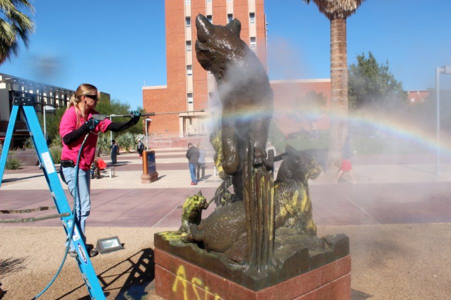 Kimberly Cain / The Daily Wildcat

Jennifer Beebe, damage restoration contractor, uses a high pressure hot water system to remove graffiti on the bronze Arizona Wildcat Family sculpture at the UA mall on Monday.