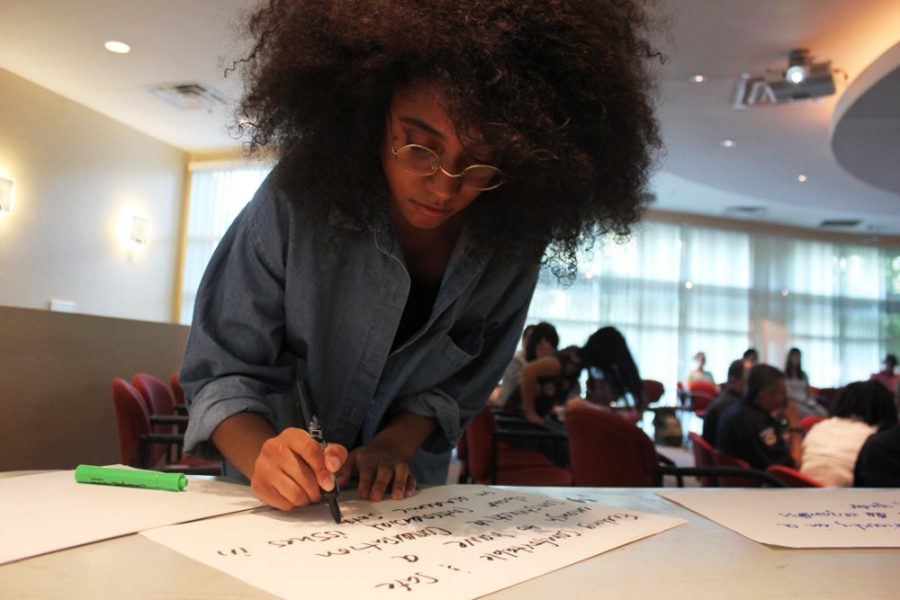 	Africana studies junior Sydney Haliburton writes a poster during the Black Student Union’s Know Your Rights forum on Wednesday in the Union Kiva room of the Student Union Memorial Center. Haliburton’s poster said, “the UA justice is feeling comfortable and safe enough to have a constructive conversation about controversial issues on academic setting.”