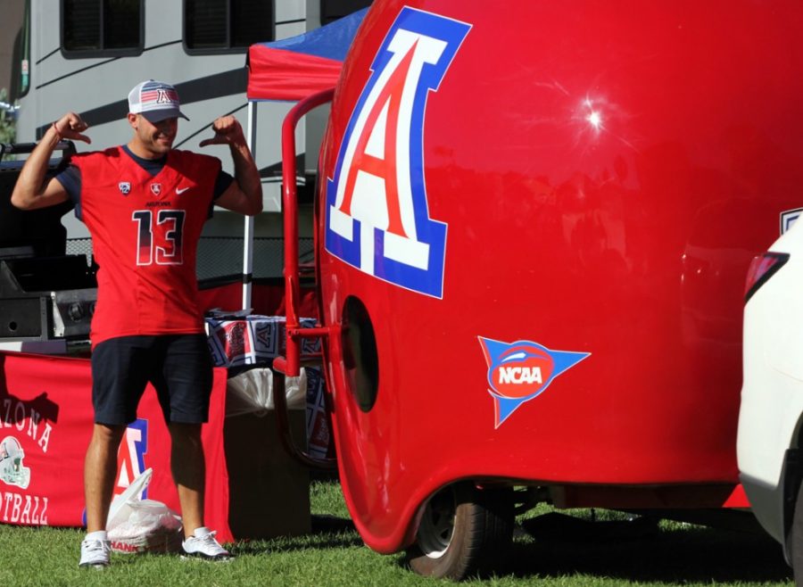 	Rebecca Marie Sasnett / The Daily Wildcat

	Senior theater major and former Wilbur Wildcat Robbie Dema poses for a photo 
next to a UA helmet while tailgating on the UA Mall before Friday’s game against the University of Nevada, Las Vegas. The helmet was built by local engineer Rafael Lopez, who’s been tailgating at UA football games for thirteen years.