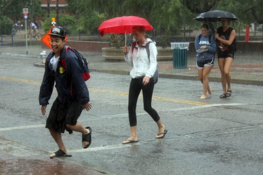 	Students on the UA campus fight the monsoon storm outside of the Park Student Union on Monday. Streets throughout campus quickly flooded.