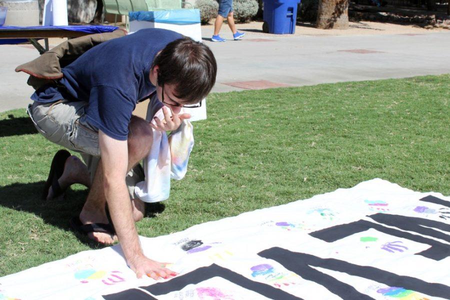 Kyle Hansen / The Daily Wildcat

Linguistics and History junior Jeremy Biedny makes a hand print on a banner that says Never Settle at the LGBTQ Coming Out Week Resource Fair on the UA mall on Monday, Oct. 13. Coming Out Week gives students support to come out to their parents and friends.