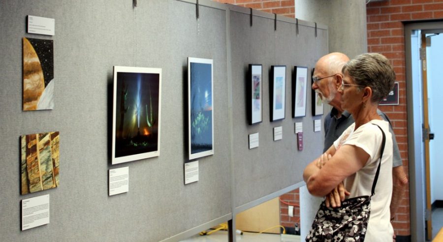 Wendell Werner, left, and Jerri Werner, right, look at different pieces of art at the Art of Planetary Science exhibit on Saturday. Images with subjects ranging from the surface of Mars to a slice of a meteorite were on display at the exhibit.