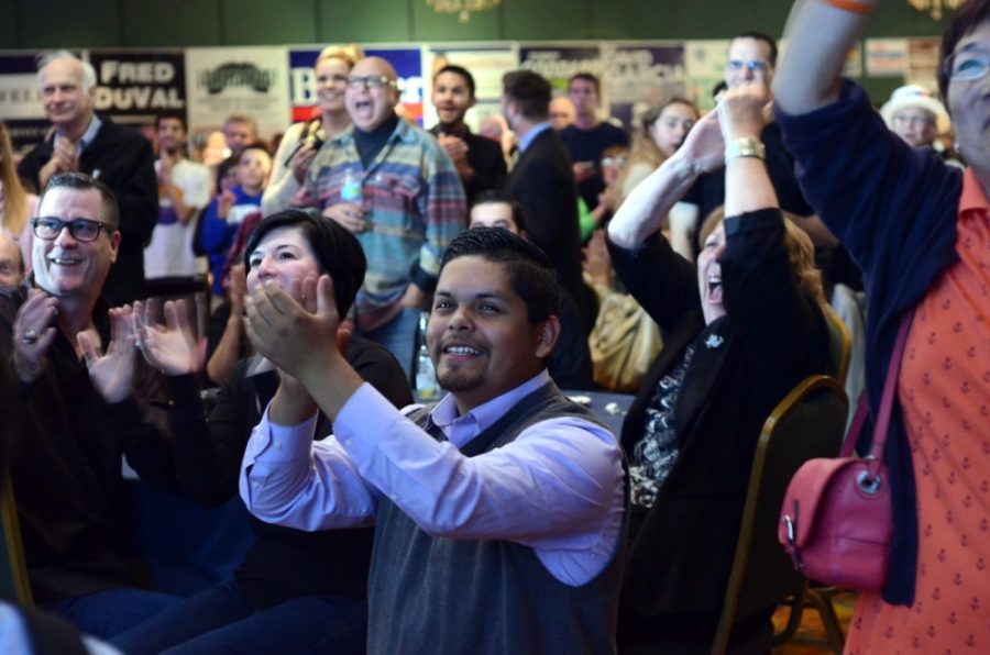 Political science senior Jose Guadalupe-Conchas rejoices as he watches the latest local polling results scroll by during Rep. Ron Barbers election party at the Tucson Marriott University Park on Tuesday. The atmosphere of Barbers election party was generally confident that the Democrat would win the race.