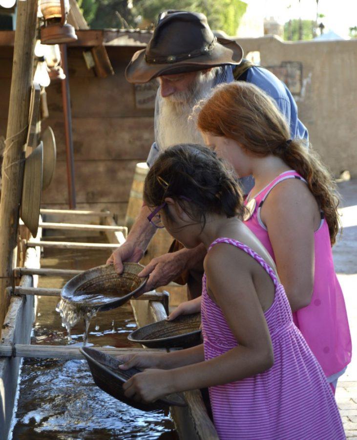 Brandi Walker/Arizona Summer WildcatBig Jim the gold panner teaches two young girls how to pan for gold at Trail Dust Town in Tucson on Friday, July 10. The Loft projected The Muppet Movie at 7:45 p.m. for children and their families.