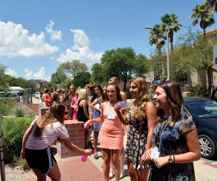 Jenna Ebert, a recruitment counselor and junior studying communications, marketing and creative writing, left, sprays the legs of potential new members lined up outside of the Delta Gamma sorority house on Thursday, August 20, 2015. Thursday was set three of recruitment, which includes skits and house tours. 