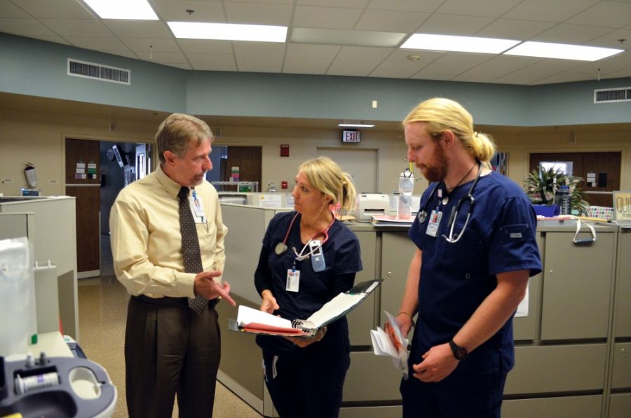 New Banner—University Medical Center  Tucson and South campuses CEO Tom Dickson, left, chats with registered nurses Victoria Smith, center, and Zachariah Coverdale, right, at their station on Monday, Aug. 31, 2015. Dickson said adding the priorities of teaching and research alongside patient care has been a new experience for him as a hospital administrator.