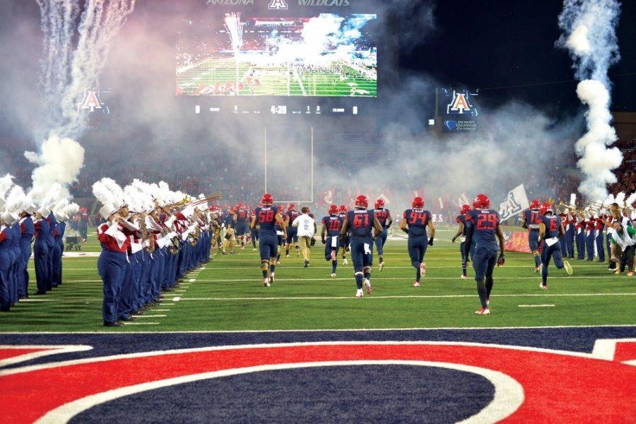 Arizona football runs onto the field through a human corridor formed by the marching band at Arizona Stadium before the 2014 Homecoming game against Colorado on Saturday, Nov. 8, 2014. 