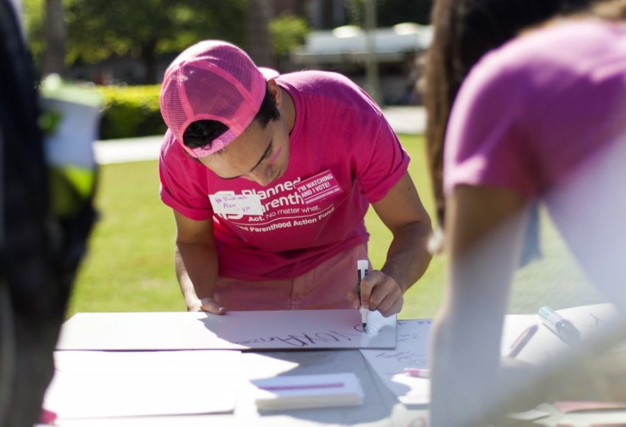 Alex Ross, vice president of VOX: Voices for Planned Parenthoods University of Arizona chapter, creates a sign on during the groups #PinkOut event at the UA Mall on Tuesday, Sept. 29.