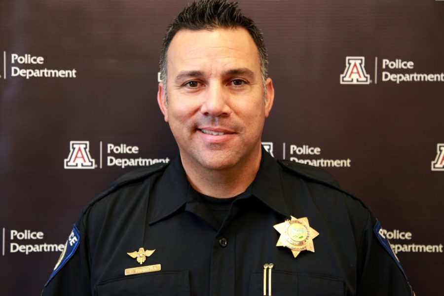 The University of Arizona Police Department Public Information Officer Sgt. Filbert Barrera stands proudly in front of the UAPD logo Nov. 11. Barrera began his career in 1998, and he said that the community and the pride of the school have contributed to him staying with UAPD for over 18 years.