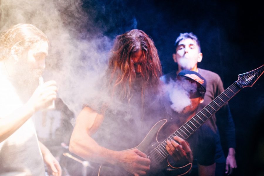 Act of Defiance guitarist Chris Broderick strums out a solo as five men with handheld vaporizers surround him and simulate a smoke machine at The Rock on Friday, Dec. 4. 