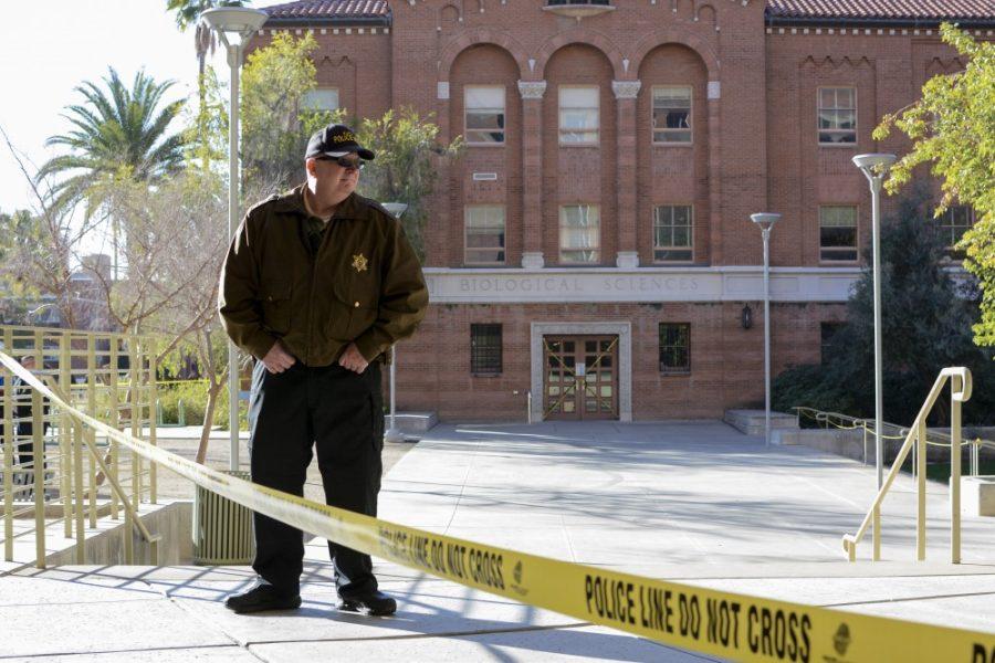 A University of Arizona police aide watches the police line and directs students to alternate routes to their classrooms outside of the Koffler building on the UA campus on Tuesday, Jan. 26.