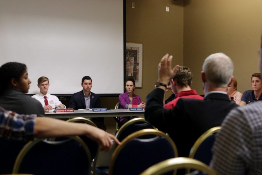 UA Provost Andrew Comrie raises his hand to make a point during the ASUA meeting on Wednesday. Comrie spoke about upcoming events at the university such as the tuition deadline and the proposed Arizona Athletics fee. 