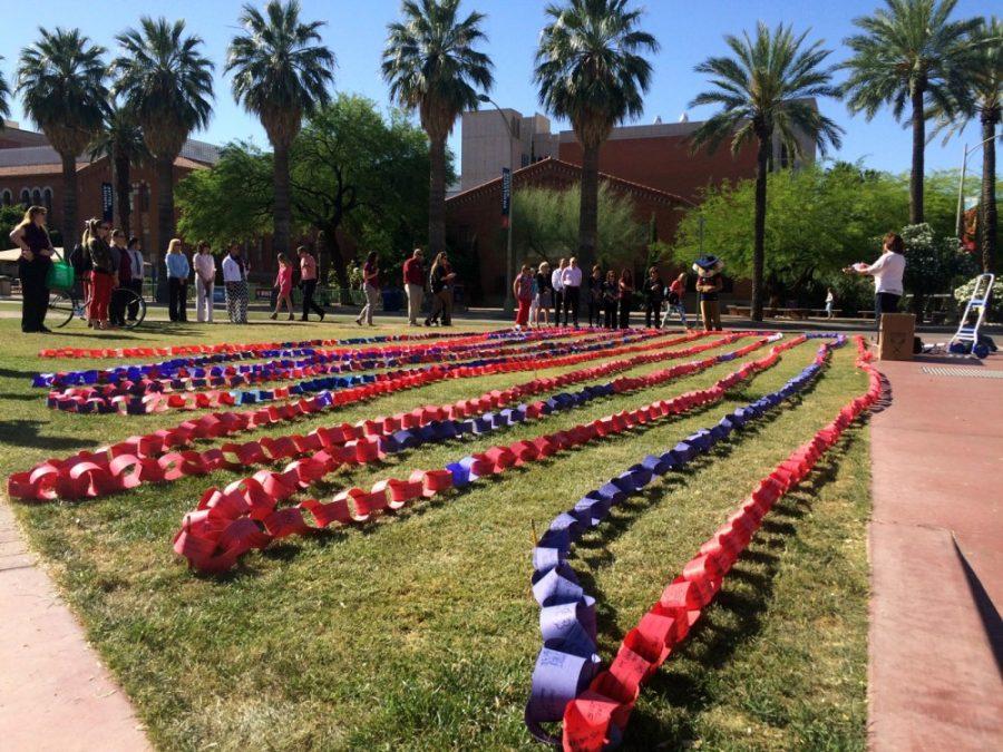 A chain of red and blue links symbolizing intentional acts of kindness lay on the grass of the UA mall.