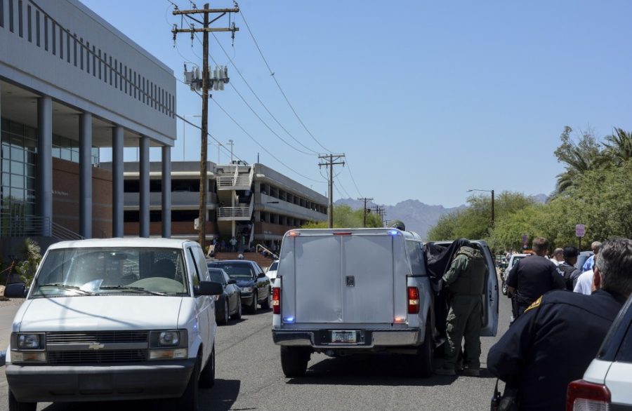 Tucson Police bomb squad technicians, in green, operate a laptop on the side of their vehicle under a sheet on Helen Street following the evacuation of McClelland Hall by UAPD and Tucson Police after a suspicious device was found on Tuesday, May 3. The building is home to the UAs Eller College of Management.